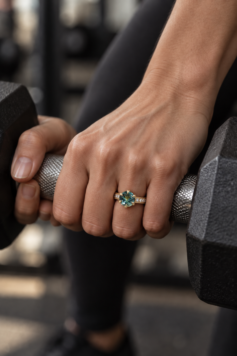 Sapphire and diamond ring on hand holding a gym dumbbell